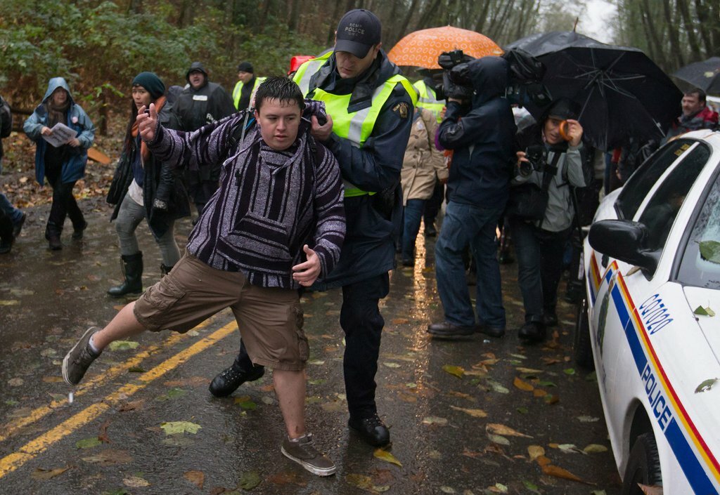 A Royal Canadian Mounted Police officer removes a protester from a road on Burnaby Mountain in British Columbia soon after Kinder Morgan began clearing trees in 2014 to make way for drilling equipment. Darryl Dyck/AP Photo/The Canadian Press