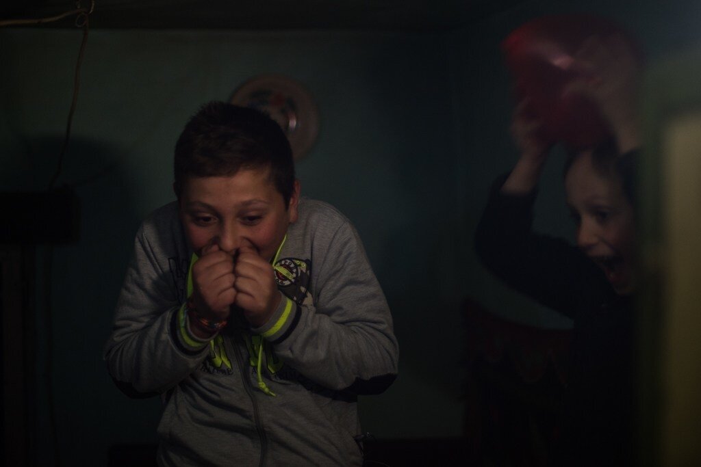 Twelve-year-old Boboc Codrut Sergiu and his six-year-old brother Boboc Serafino Oliver play with balloons in the dark after sunset. “We are scared to step out of the house in the dark,” Sergiu says.